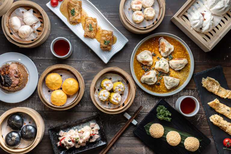 A table of Dong Sing dim sum including Har Gow, Siew Mai, Shumai, Hong Kong Seafood Shrimp Mai, Lo Mai Gai, Pan-Fried Dumplings, Shrimp Roll, BBQ Chicken Bun, Dim Sum Steamed Spare Ribs, Steamed Buns, Creamy Salted Egg Bun, Dumplings, and other dim sum varieties